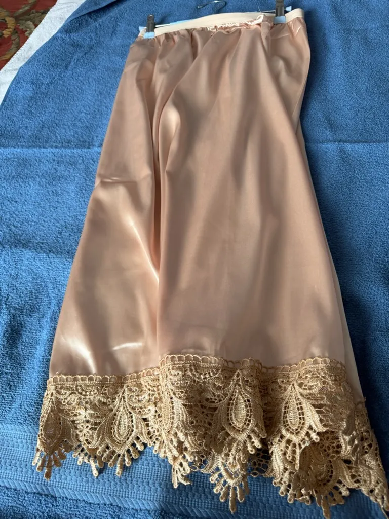 Full view of handmade lingerie in breathable champagne satin with a scalloped gold lace hem.